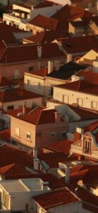 An aerial view of terracotta rooftops and white buildings in warm golden light